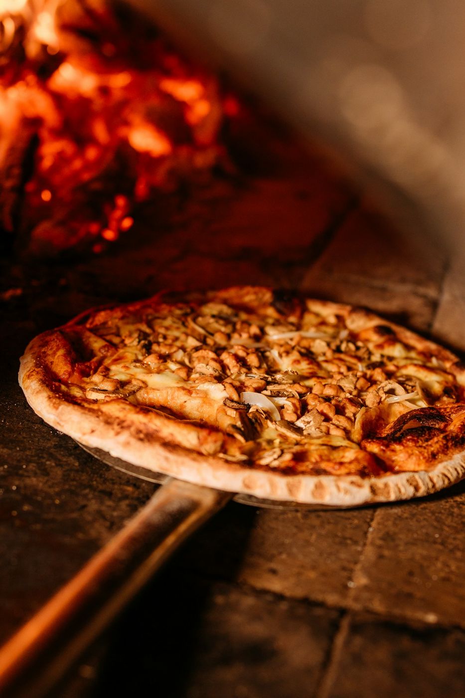 Pizza che esce dal forno a legna